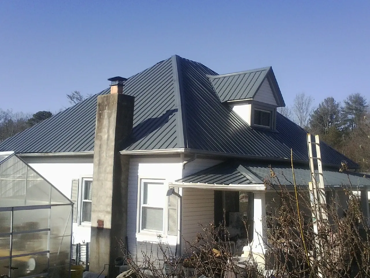 Dark blue standing seam metal roof on a white farmhouse with dormer — Slate & Tile Roof Repair by Roofing Brothers in Heyburn