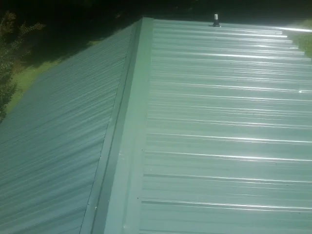 New green metal panels meeting at the ridge of a roof — Flat Roof Repair work by our crew in Heyburn