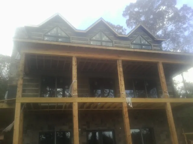 Dormers and porch framing on a large log home under construction — Roof Coating work by our crew in Heyburn