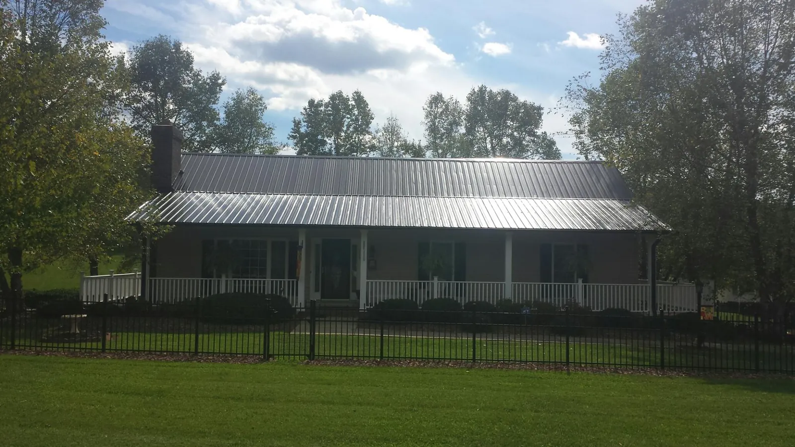 Gray metal roof on a brick ranch with a full width front porch — Gutter Guard Installation work by our crew in Heyburn