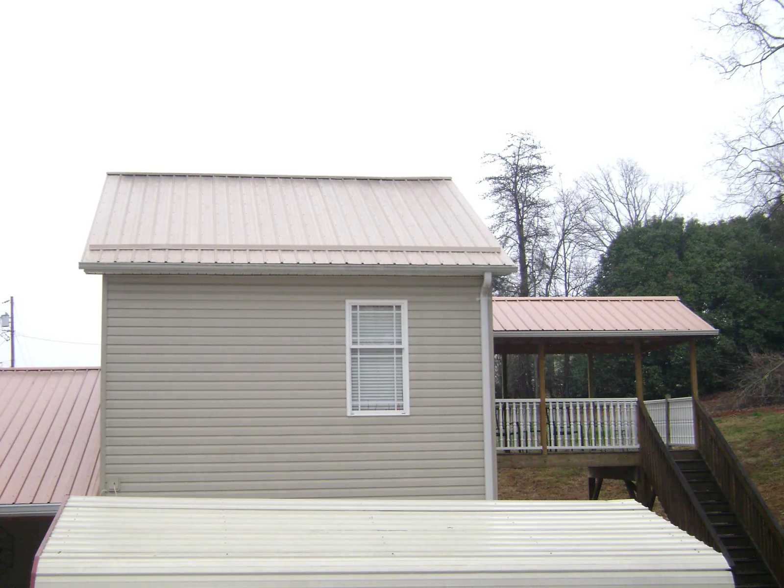 Tan metal roofs on a two story addition and attached porch, from a Roof Replacement job in Heyburn