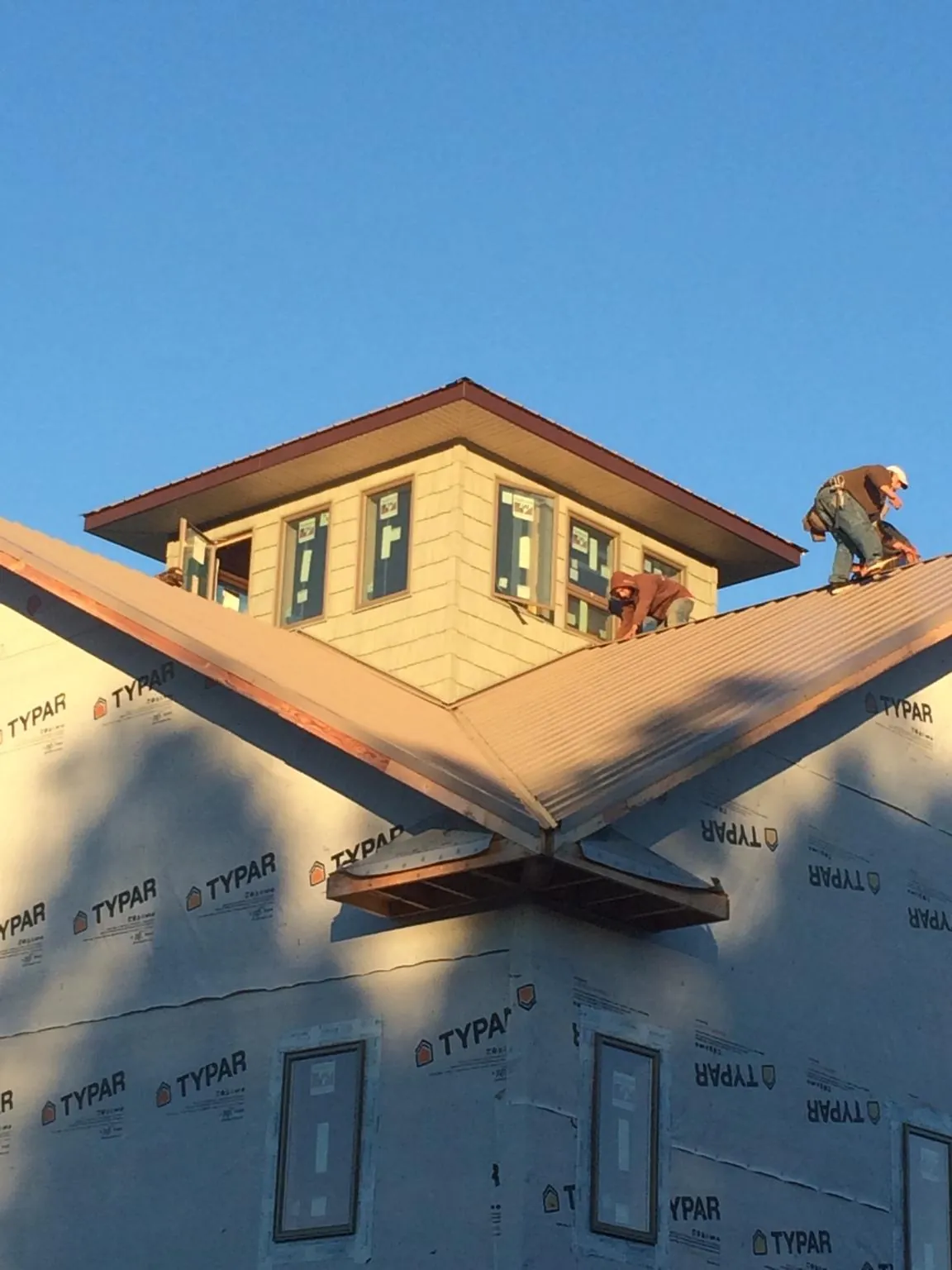 Roofers working around a rooftop cupola on a new metal roof at sunset — Roof Waterproofing in Heyburn by Roofing Brothers